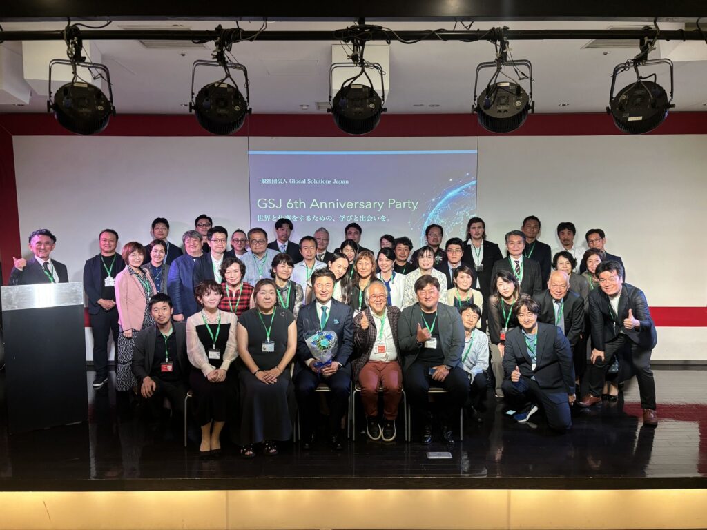 GSJ 6周年纪念派对的集体合影。舞台屏幕上显示「GSJ 6th Anniversary Party」,与会者在屏幕前排列合影