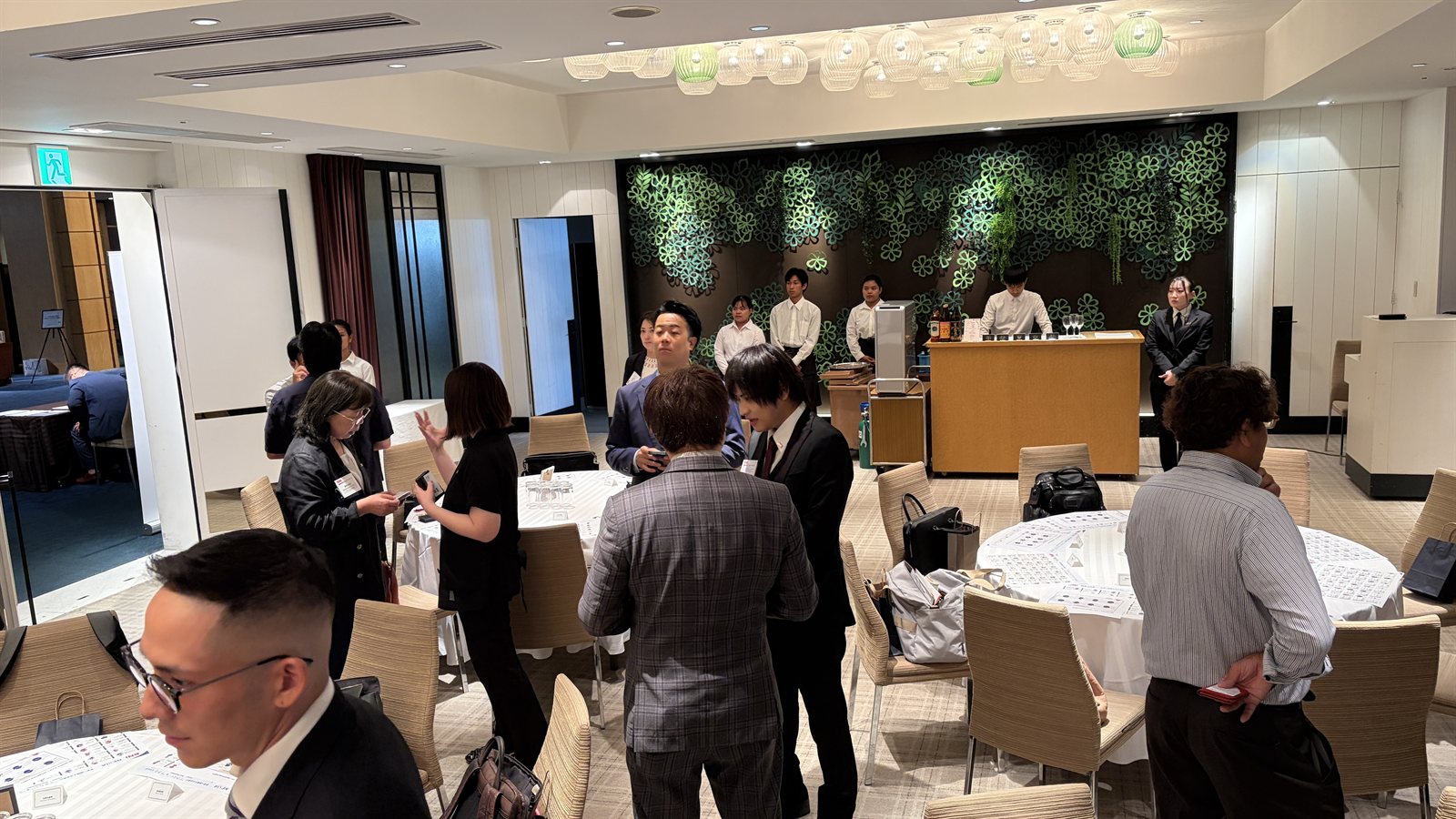 成立纪念派对会场的交流场景,与会者站立交谈、交换名片